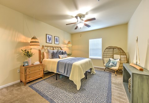 A bedroom with a bed, a chair, and a ceiling fan at Cabana Club - Galleria Club Apartments, Florida 32256